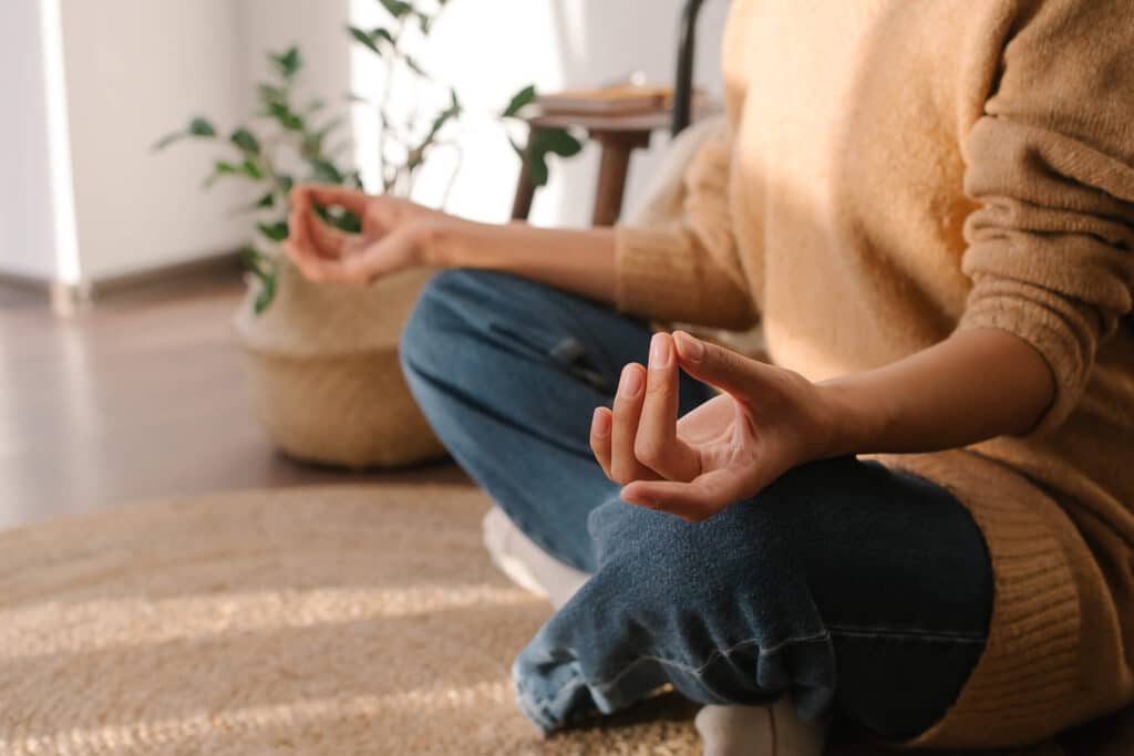 A woman sitting on the floor gracefully meditating in a yoga pose
