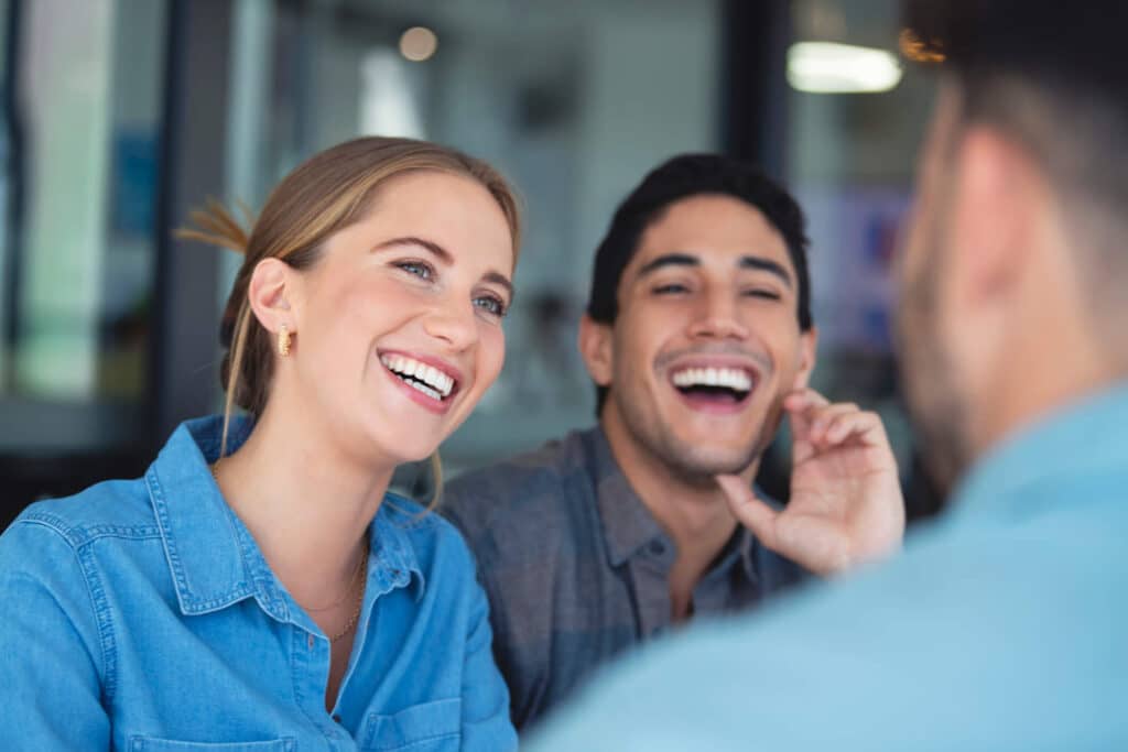 A man and woman share a joyful moment, laughing together during a therapy meeting.