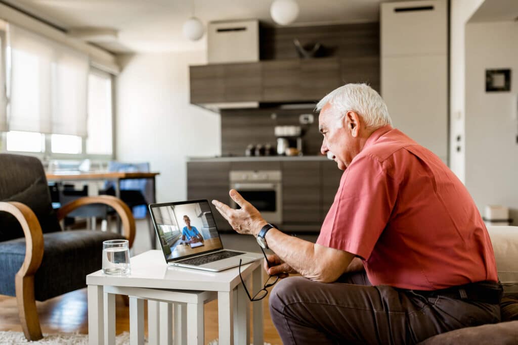 A elderly man sitting down talking to someone through a video call