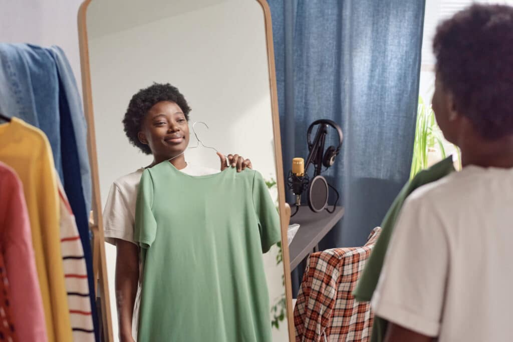A woman smiling in front of the mirror while fitting a green dress